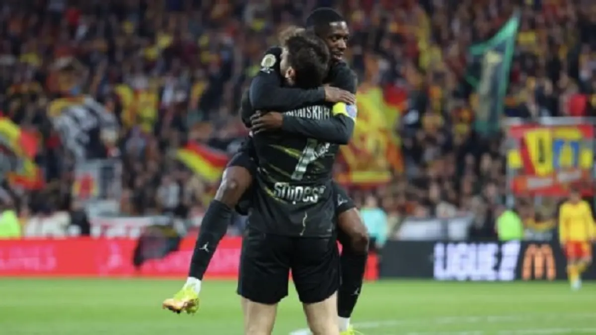 Khvicha Kvaratskhelia dipeluk oleh Ousmane Dembélé setelah mencetak gol untuk PSG melawan Lens. (Xavier Laine/Getty Images)