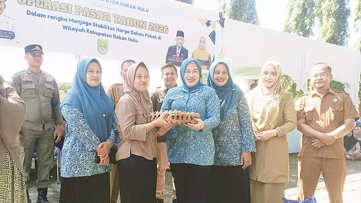 Ketua TP PKK Rohul dr Yeni Dwi Putri didampingi Plt Kadis Perindag Rohul Sugesti menyerahkan secara simbolis bahan pokok yang dibeli masyarakat dalam kegiatan operasi pasar di halaman kantor Camat Bangun Purba, Selasa (19/5/2026). (Dinas Kominfo Rohul untuk Riau Pos)