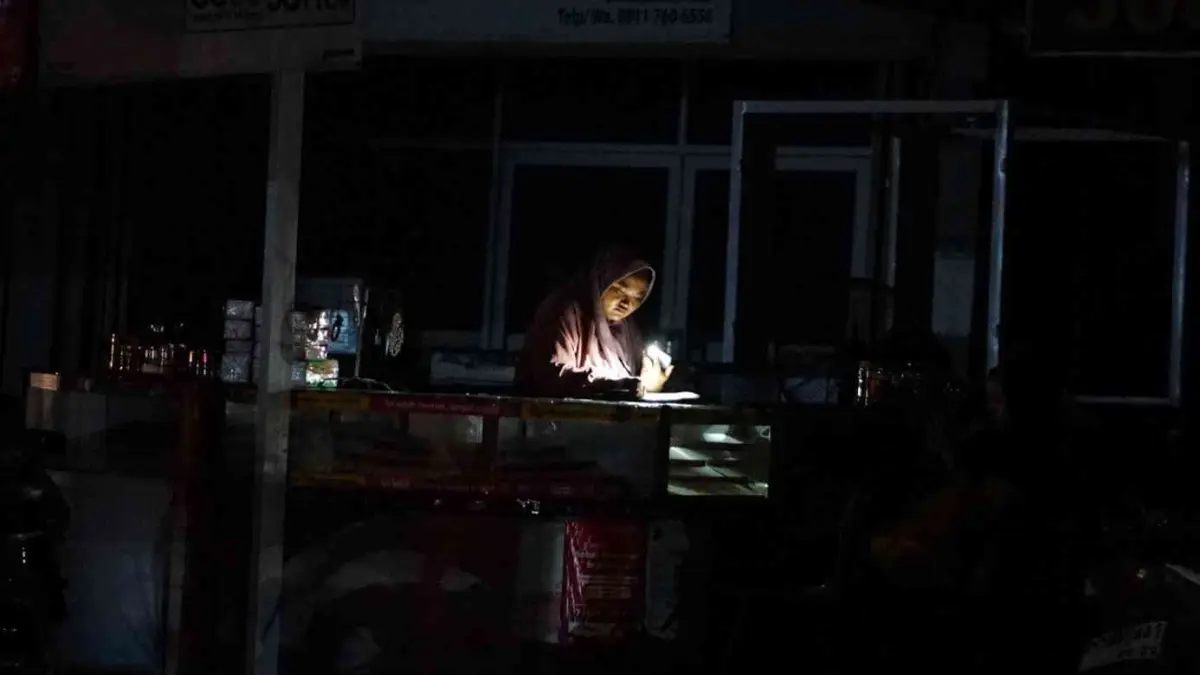 Warga Pekanbaru menggunakan senter saat menerangi tempat usahanya di Jalan Srikandi Pekanbaru, Jumat (22/5/2026).(EVAN GUNANZAR/RIAUPOS.CO)