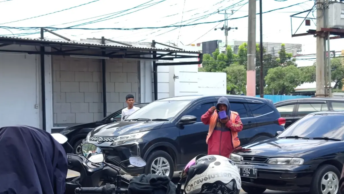 Tampak Oknum jukir tengah beroperasi meminta pungutan parkir di Indomaret Jalan HR Soebrantas Panam, Selasa (26/5/2026). (M Akhwan/Riau Pos)