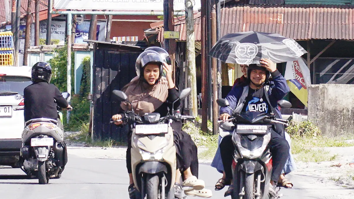 Pengendara menggunakan payung saat melintas di Jalan Inpres, Pekanbaru untuk menghindari paparan cahaya panas matahari, Ahad (31/5/2026). (MHD AKHWAN/RIAUPOS)