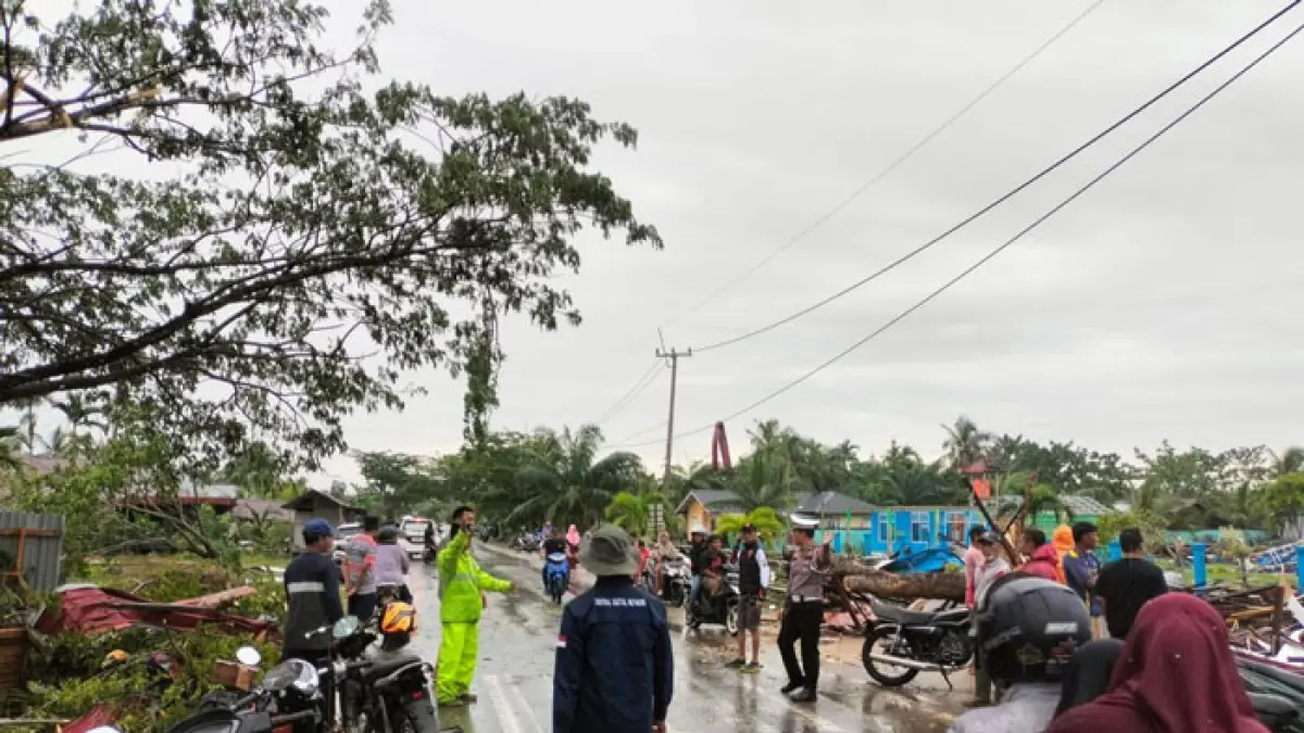 Petugas Lalulintas Polres Bengkalis bersama personel polisi lainnya sedang melakukan pengamanan arus lalulintas serta membantu memindahkan material bangunan akibat hantaman angin puting beliung di Desa Api-api, Ahad (7/6/2026) sore. (Istimewa)