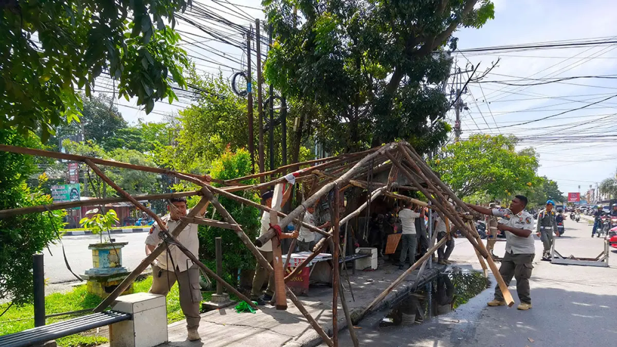 BONGKAR LAPAK: Petugas Satpol PP Pekanbaru melakukan pembongkaran lapak-lapak PKL yang berada di sepanjang jalur lambat Jalan HR Soebrantas Panam, Rabu (10/6/2026). (EVAN GUNANZAR/RIAU POS) 
