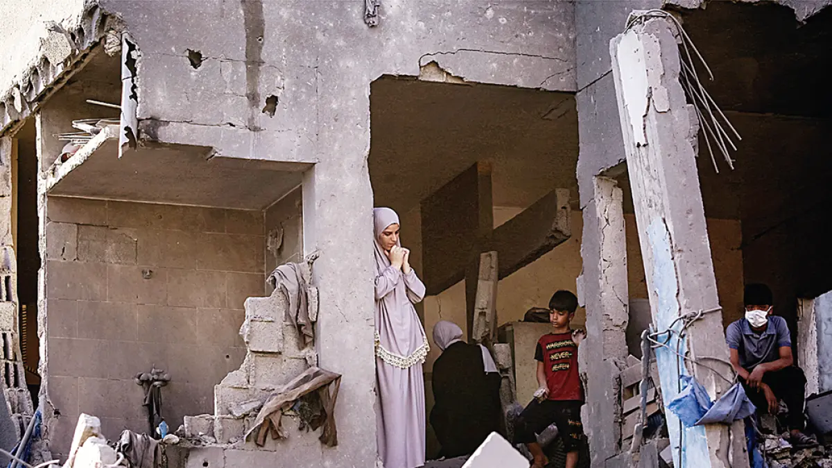 Seorang wanita dan anak berdiri dekat reruntuhan bangunan yang hancur akibat bombardir Israel di kamp pengungsi Palestina Maghazi, Jalur Gaza Tengah, Jumat (12/6/2026).(AFP)