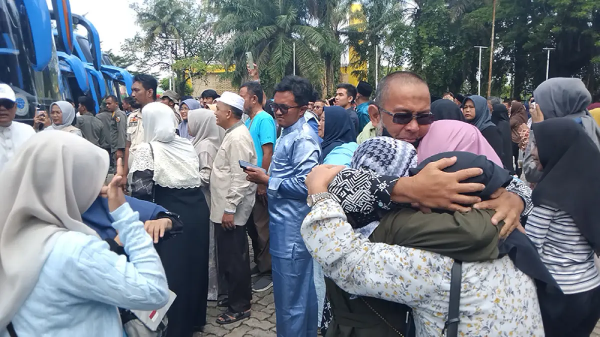 Seorang jemaah haji Riau Kloter 18 memeluk kerabatnya usai turun dari bus yang tiba di Kompleks Bandar Seni Raja Ali Haji  atau purna-MTQ Jalan Sudirman Pekanbaru, Ahad (21/6/2026). (KEMENHAJ RIAU UNTUK RIAU POS)
