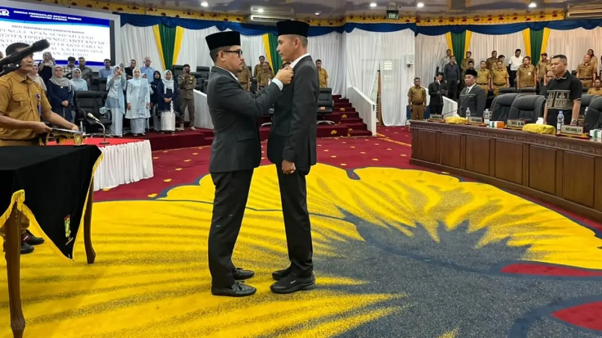 Wakil Ketua I DPRD Kabupaten Kampar Iib Nursaleh memasang PIN anggota DPRD kepada PAW dari Fraksi PAN Idris di ruang rapat paripurna DPRD Kabupaten Kampar, Senin (22/6/2026). (Kamaruddin/Riaupos.co)