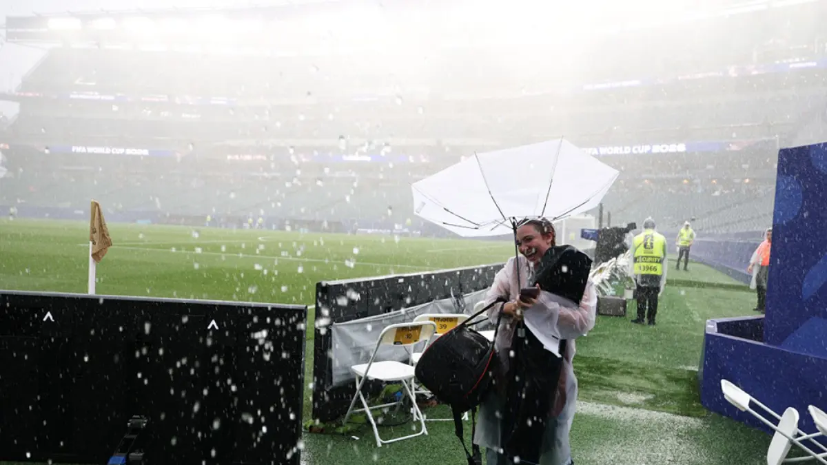 Seorang fotografer memegang payung dan melindungi diri dari hujan saat pertandingan antara Prancis melawan Irak  di Stadion Philadelphia, Senin (22/6/ 2026).  (FRANCK FIFE/AFP)