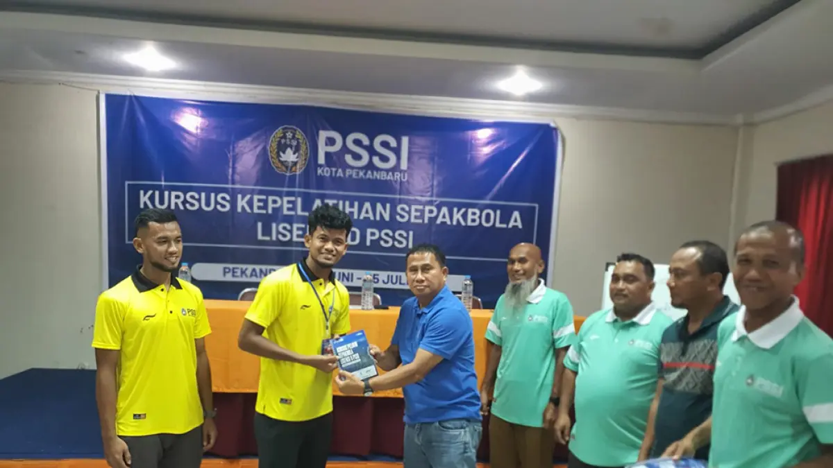 Direktur Departemen Pengembangan Teknik PSSI Pekanbaru Philep Hansen Maramis menyerahkan buku kepada perwakilan peserta Ilham Fathoni usai penyematan ID card saat pembukaan Kursus pelatih sepakbola lisensi D yang digelar PSSI Pekanbaru, Senin (29/6/2026). (PSSI PEKANBARU UNTUK RIAU POS)
