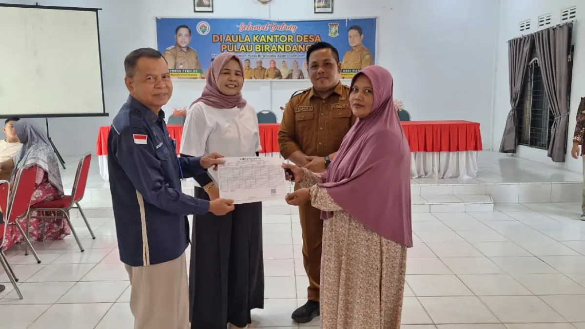 Kepala Disdukcapil Kampar Muslim menyerahkan secara simbolis Kartu Keluarga kepada sejumlah warga penerima layanan di Pulau Berandang, Kecamatan Kampa, Selasa (30/6/2026).(DISDUKCAPIL KAMPAR UNTUK RIAUPOS.CO)