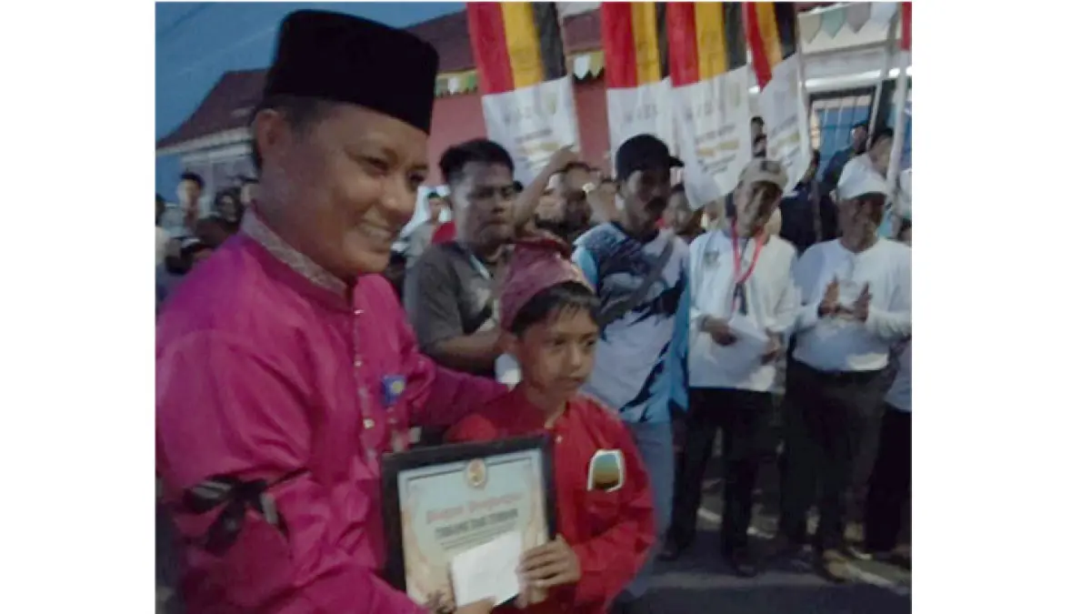 Camat Kuantan Tengah Eka Putra SSos MSi menyerahkan Si Tukang Tari Terbaik Pacu Jalur Rayon II di Tepian Narosa Telukkuantan, Selasa (30/6/2026). (Panpel Pacu Jalur)