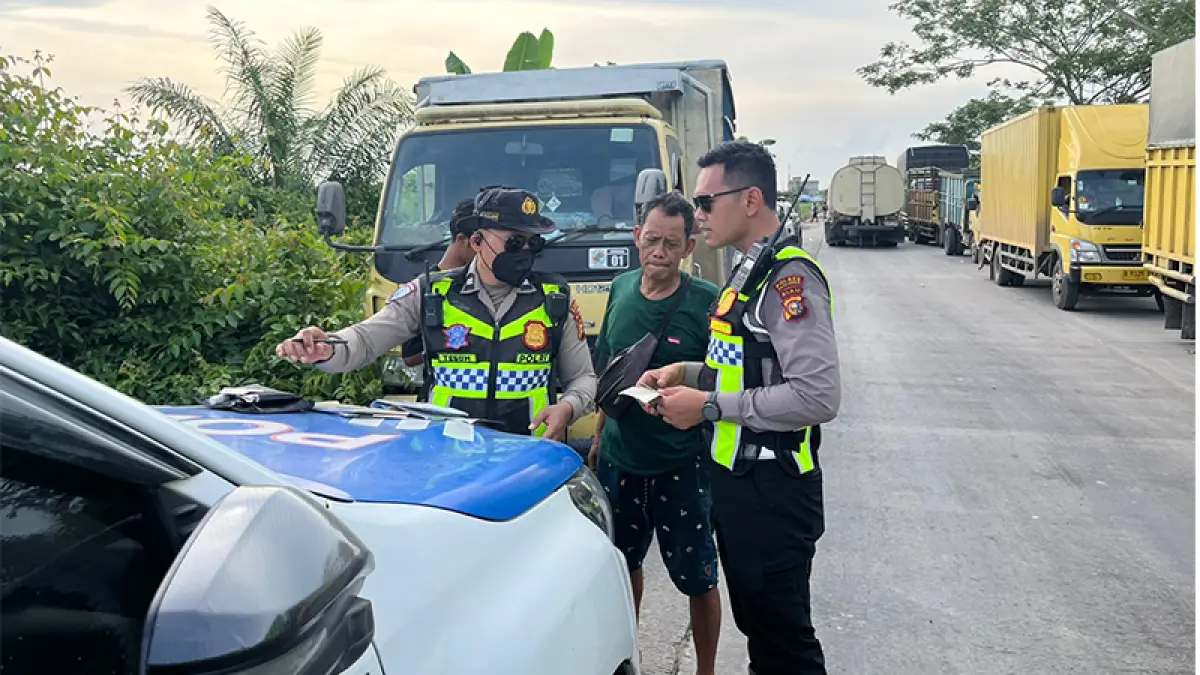 Personel Sat Lantas memberikan tilang kepada penerobos antrean di Jalan Lintas Timur Km 75 Kecamatan Pangkalan Kerinci yang menyebabkan terjadinya kemacetan panjang, Senin (1/7/2026). (M Amin Amran)