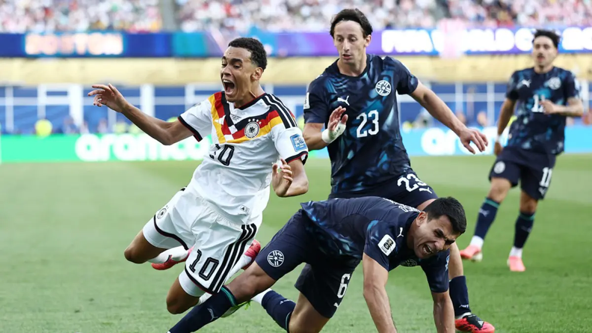 Gelandang Jerman Jamal Musiala dan bek Paraguay Junior Alonso ter­jatuh saat berebut bola dalam pertandingan babak 32 besar Piala Dunia 2026 di Stadion Boston, Foxborough, Selasa (30/6/2026). (CHARLY TRIBALLEAU/AFP)