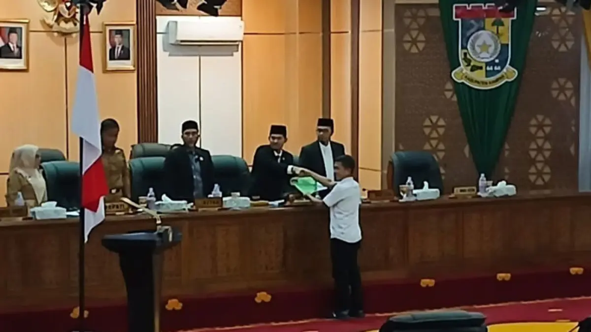 Ketua Fraksi Nasdem Eko Sutrisno menyerahkan laporan tanggapan Fraksi Nasdem kepada Wakil Ketua I Iib Nursaleh saat rapat paripurna di ruang rapat paripurna DPRD Kampar, Senin (6/7/2026). (Kamaruddin/Riaupos.co)