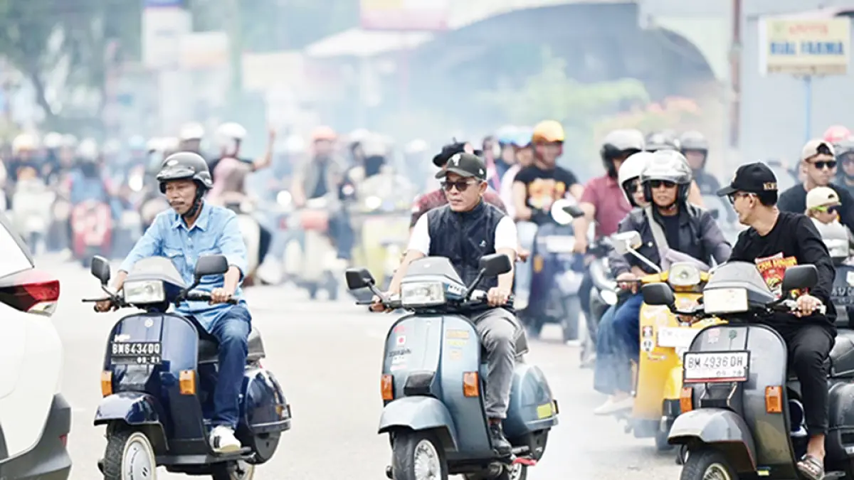 IKUT KONVOI: Staf Ahli Bupati Bengkalis Syahruddin ikut pawai konvoi Vespa mengelilingi Kota Bengkalis dengan pengawalan aparat kepolisian melintasi jalanan Kota Bengkalis, Ahad (12/7/2026). (Pemkab bengkalis untuk riau pos)
