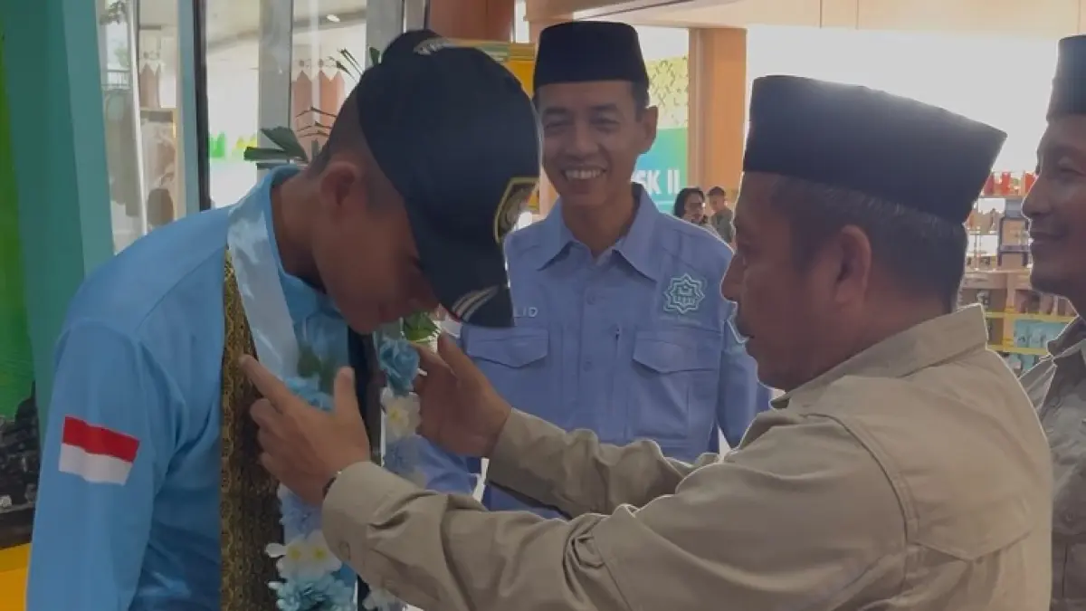 Kepala Kantor Wilayah Kementerian Agama Provinsi Riau Muliardi saat mengalungkan karangan bunga kepada siswa MAN IC Siak Rizqy Aditya Siregar saat melepas keberangkatan paskibraka tingkat pusat di Bandara SSK II Pekanbaru, Selasa (14/7/2026). (Humas MAN IC Siak untuk Riau Pos)