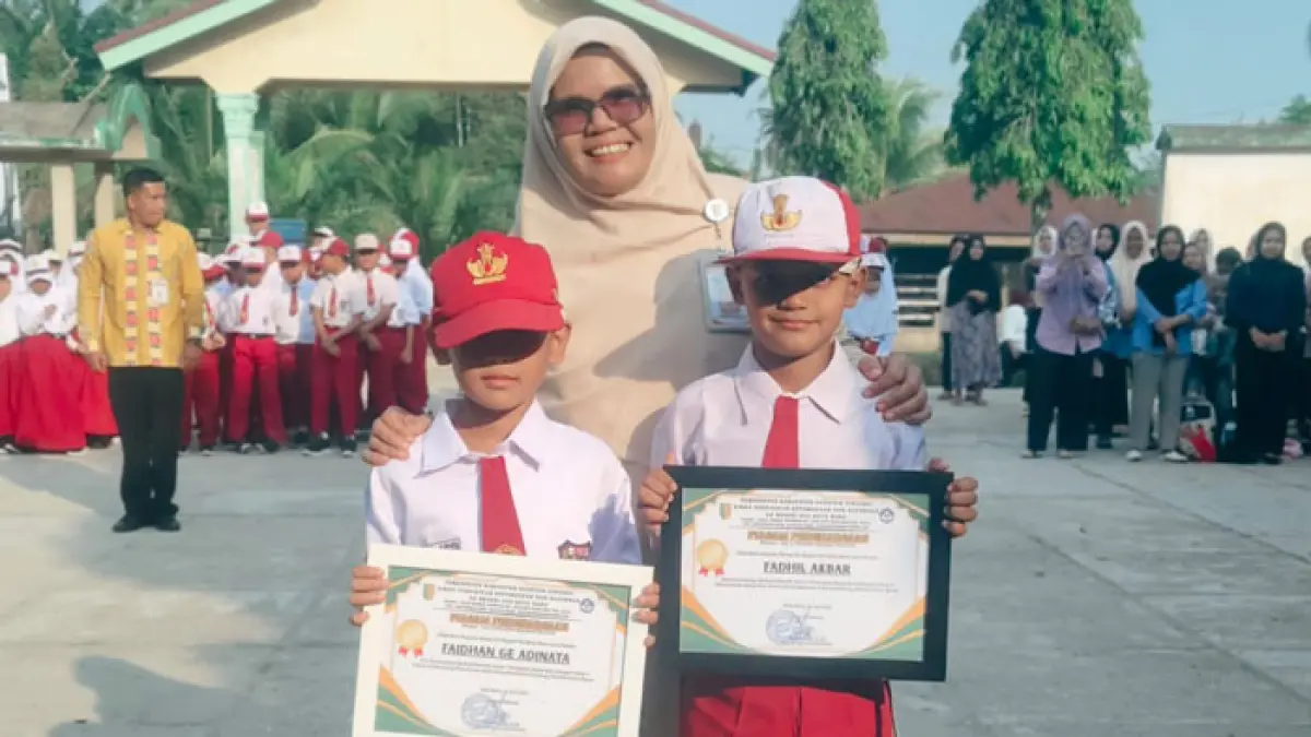 Kepala SDN 02 Singingi Hilir Mardianis SPd bersama kedua muridnya, Fadhil Akbar dan Faidhan GE Dinata yang lolos seleksi U-9, Senin (13/7/2026) usai upacara. (Disdikpora Kuansing untuk Riaupos.co)
