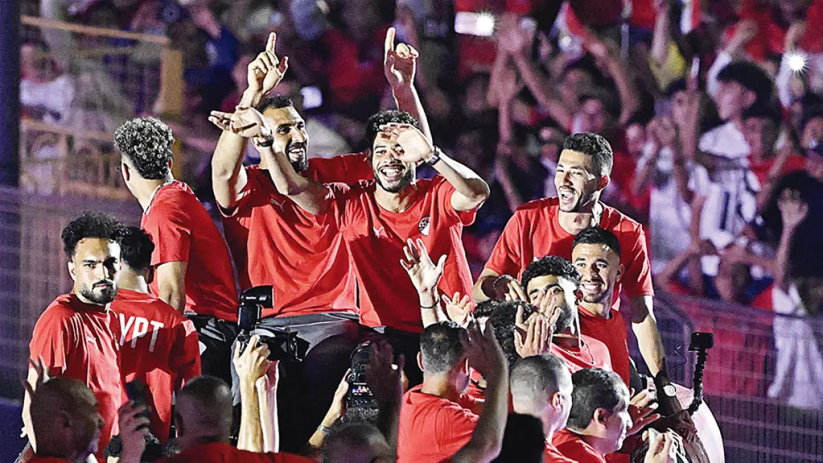 Para pemain Mesir melambaikan tangan dari bus beratap terbuka ke arah para penggemar yang bersorak saat mereka memasuki Stadion Kairo, Senin (13/7/2026), setelah berpartisipasi dalam turnamen sepakbola Piala Dunia FIFA 2026.  (Khaled DESOUKI/AFP)
