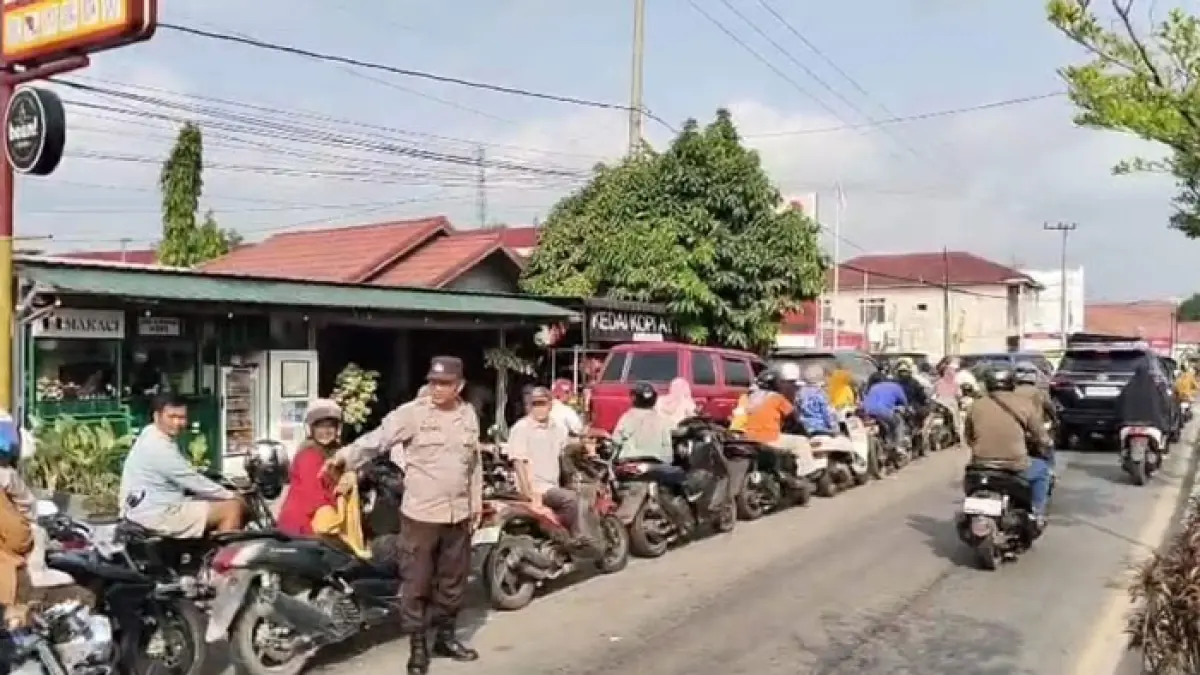 Anggota Polsek Kuantan Tengah AIPTU Elpino Tanio ikut mengatur antrean kendaraan di SPBU Sungai Jering Kecamatan Kuantan Tengah, Jumat (17/7/2026). (Desriandi Candra/Riaupos.co)