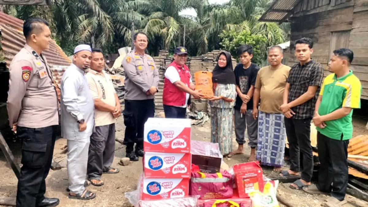 Camat Kepenuhan Gustia Hendri didampingi Kapolsek Kepenuhan Iptu Jonnes SH menyerahkan bantuan Pemkab Rohul kepada korban Mariani yang rumahnya hangus terbakar di Desa Ulak Patian, Sabtu (18/7/2026) siang. (Dinas Kominfo Rohul untuk Riaupos.co)