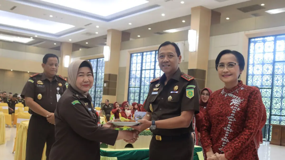 Kajati Riau I Dewa Gede Wirajana, didampingi Ketua IAD Wilayah Riau Ny Oktaria Wirajana, menyerahkan tumpeng Peringatan HBA ke-66 ke Jaksa Senior Gusnely, Rabu (22/7/2026). (Humas Kejati Riau untuk Riaupos.co)