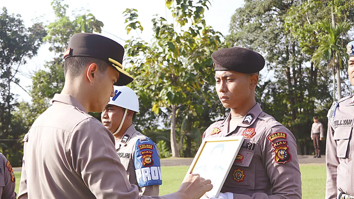 BERIKAN TANDA SILANG: Kapolres Kuansing AKBP Hidayat Perdana SH SIK MH memberikan tanda silang pada foto personel yang dicopot  dalam upacara di halaman Mapolres Kuansing, Rabu (22/7/2026). (DESRIANDI CANDRA/RIAU POS)