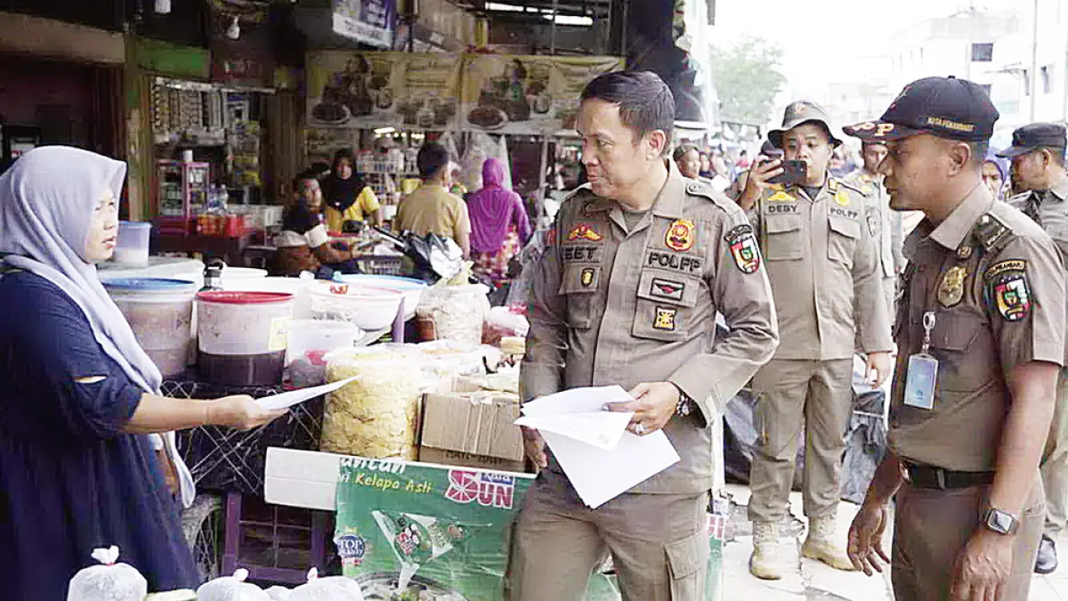 SURAT PERINGATAN: Petugas Satpol PP Pekanbaru memberi surat peringatan kepada pedagang yang berjualan di sepanjang Jalan Teratai Ujung, Pekanbaru, Senin (27/7/2026). (Satpol PP pekanbaru untuk Riau Pos)