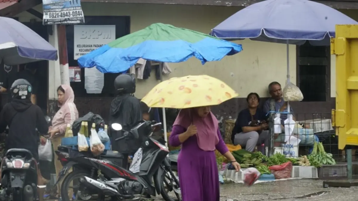 Warga kenakan payung saat hujan ketika melintas di Jalan Teratai ujung saat hujan mengguyur Kota Pekanbaru, Kamis (30/7/2026). (MHD AKHWAN/RIAUPOS.CO)