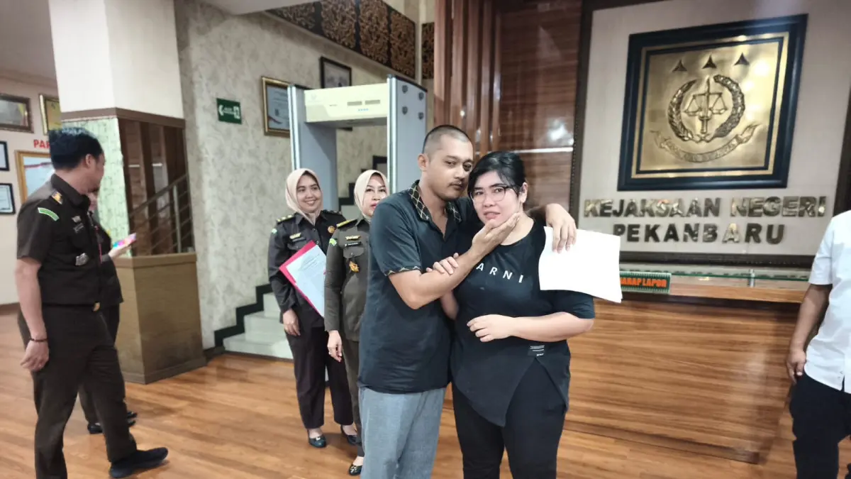 Aldo Randistya Hutagalung (kiri) memeluk sang istri, Senin (3/8/2026), usai usulan pemberhentian perkaranya lewat Restoratif justice diterima Jaksa Agung.(HUMAS KEJARI PEKANBARU UNTUK RIAUPOS.CO)
