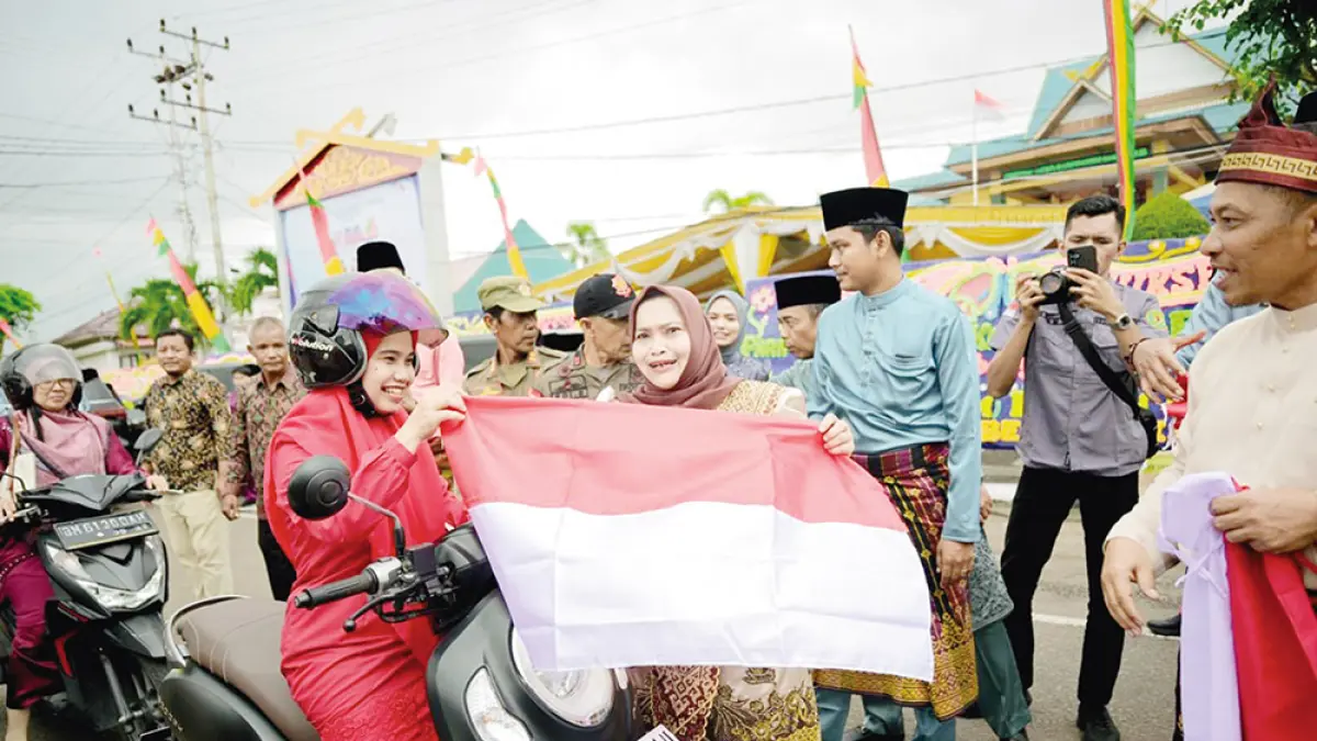 BAGIKAN BENDERA: Bupati Bengkalis Kasmarni membagikan bendera Merah Putih kepada pengendara di Jalan Antara depan Gedung DPRD Kabupaten Bengkalis, Sabtu (1/8/2026). (ABU KAMIS/RIAU POS)