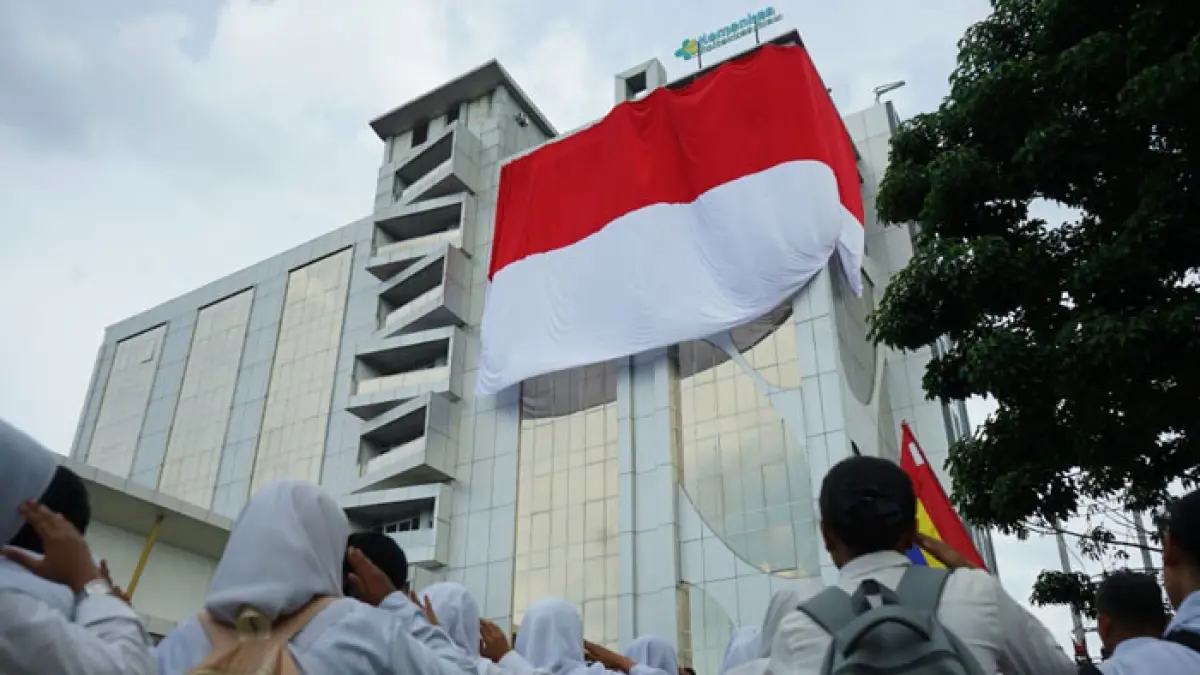 Peserta upacara menyaksikan pengibaran bendera merah putih raksasa di gedung Menara Poltekkes Kemenkes Riau, Kamis (6/8/2026). (Evan Gunanzar/Riaupos.co)