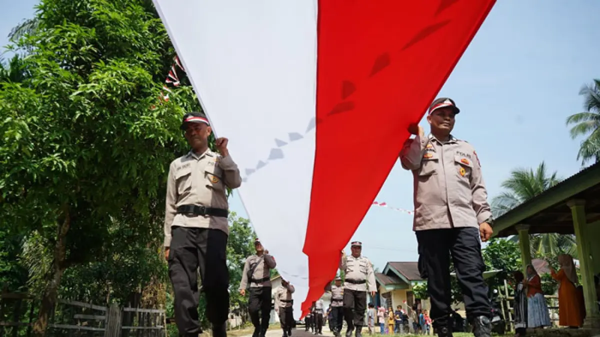 Petugas kepolisian mengarak bendera raksasa sepanjang 81 meter di Desa Tanjung Belit Selatan, Kecamatan Kampar Kiri, Senin (10/8/2026). (Evan Gunanzar/Riaupos.co)