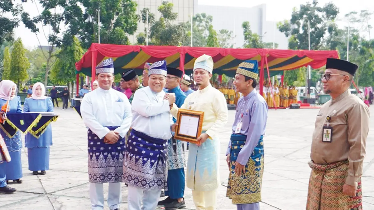 SERAHKAN PENGHARGAAN: Plt Gubri SF Hariyanto menyerahkan penghargaan kepada Wali Kota Pekanbaru Agung Nugroho usai Upacara Hari Jadi Riau di halaman Kantor Gubernur, Ahad (9/8/2026). (Diskominfo Riau untuk riau pos)
