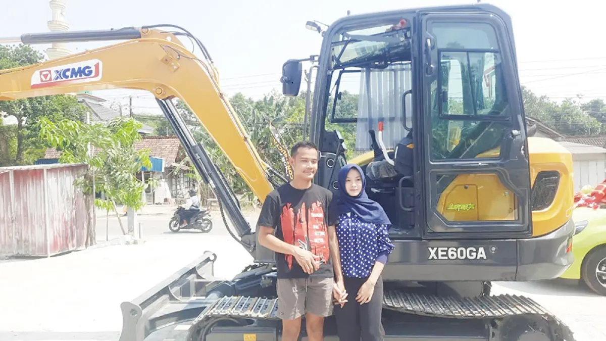 Rico Putra Robertosyah dan Laella Nur Fadhillah berdiri di samping ekskavator yang dijadikan mahar pernikahan mereka. (INTAN MAYLANI SABRINA/JPG)