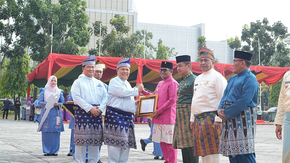 Plt Gubri SF Hariyanto menyerahkan Penghargaan Pembangunan Daerah terbaik I untuk Kategori Perencanaan dan Pencapaian Daerah Tingkat Kabupaten kepada Bupati Pelalawan H Zukri, di tengah Upacara HUT ke-69 Provinsi Riau di halaman Kantor Gubernur Riau, Ahad (9/8/2026). (intimewa)
