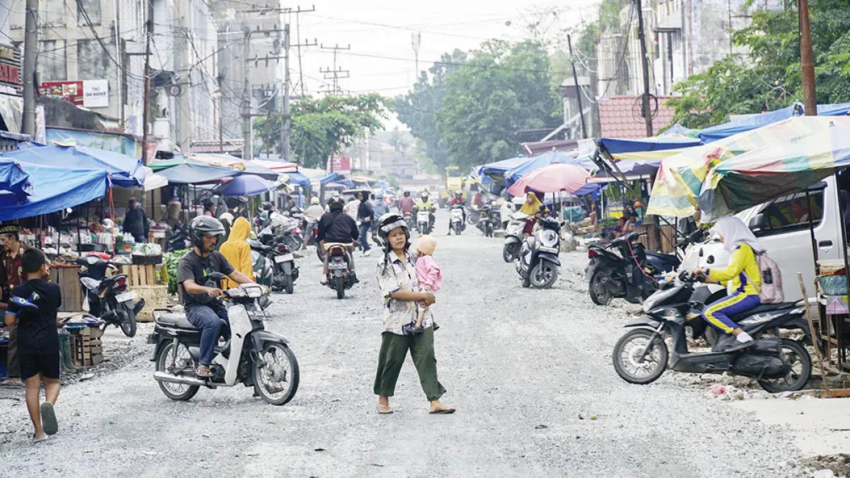 PENGERASAN JALAN: Warga melintas di Jalan Teratai Ujung, Pekanbaru, yang sedang dilakukan pengerasan base jalan sebelum diaspal ulang, Kamis (13/8/2026). (MHD AKHWAN/RIAUPOS)