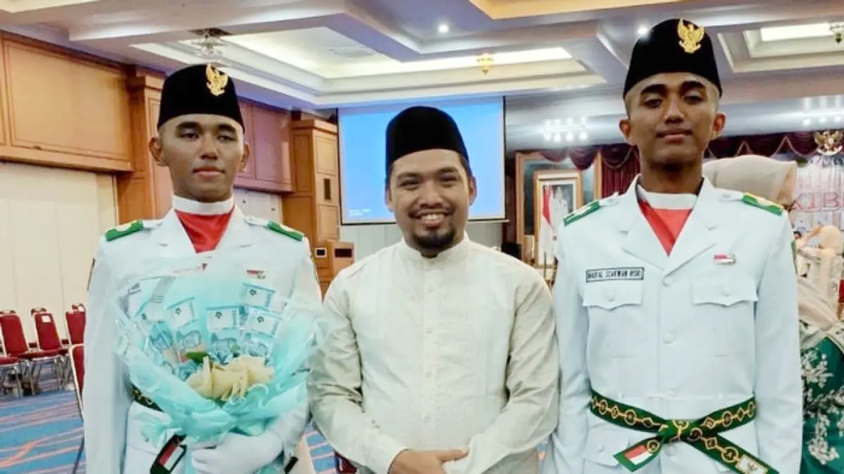 Kepala MAS Tahfidz Rohul Syukron Jamil foto bersama dua siswanya, Naufal Zakwan Riski dan Fahri Razaq, usai dikukuhkan sebagai anggota Paskibraka tingkat Kabupaten Rohul oleh Bupati Rohul Anton di Convention Hall Islamic Center Rohul, Sabtu (15/8/2026). (Engki Prima Putra untuk Riaupos.co)