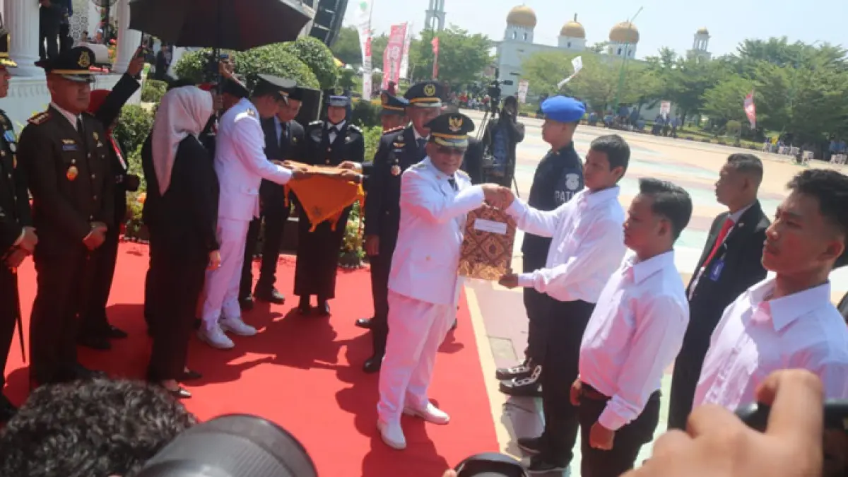 Bupati Rohil H Bistamam secara simbolis menyerahkan surat remisi kepada perwakilan WBP Lapas Bagansiapiapi, di Lapangan Purna MTQ Batu Enam, Bagansiapiapi, Senin (17/8/2026). (Zulfadhli/Riaupos.co)