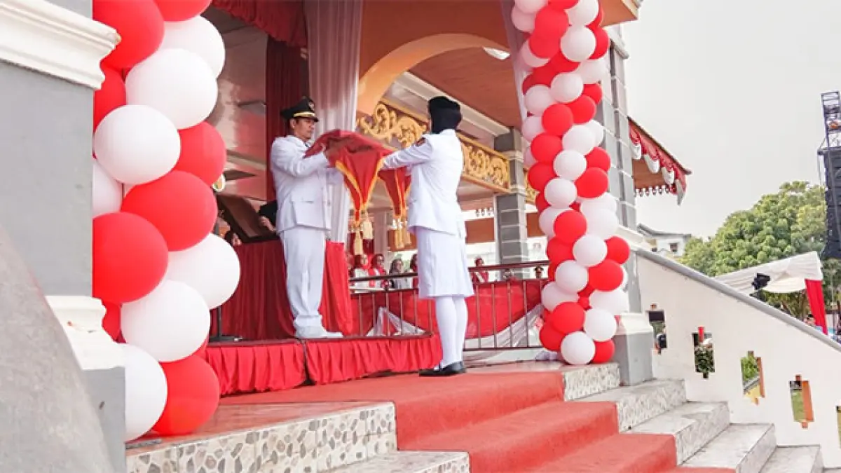 Plt Bupati Kuansing H Muklisin menyerahkan bendera Merah Putih pada pengibar bendera saat peringatan HUT Kemerdekaan RI ke-81 di Lapangan Limuno Teluk Kuantan, Senin (17/8/2026). Foto Desriandi Candra