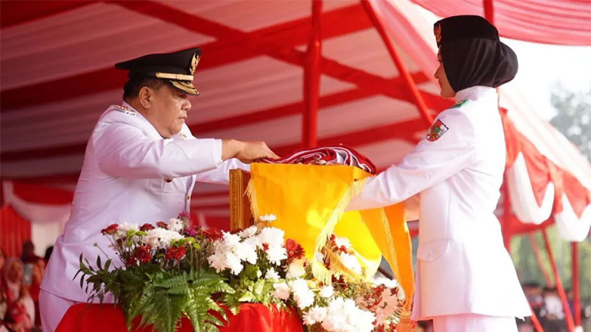 Plt Gubri SF Hariyanto menyerahkan bendera kepada petugas Paskibraka di halaman Kantor Gubernur Riau, Senin (17/8/2026). Diskominfo Riau