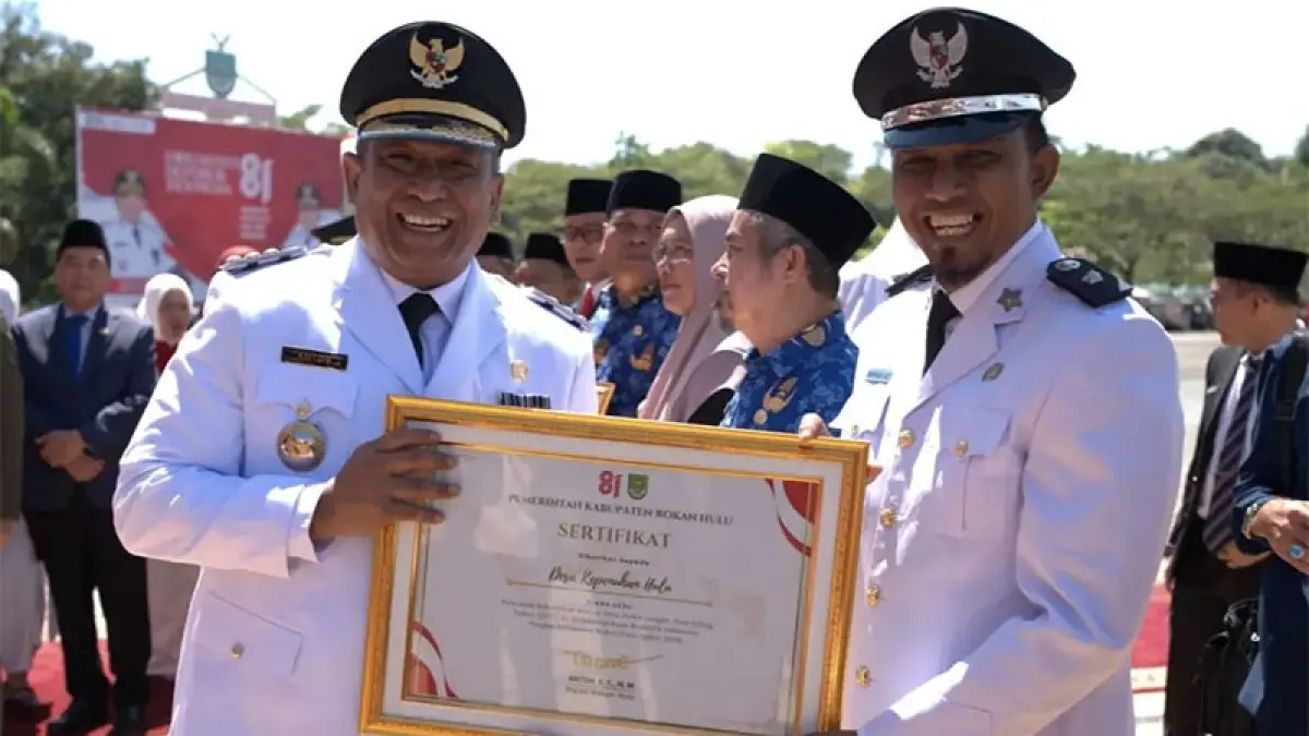 Bupati Anton menyerahkan piagam penghargaan kepada Kades Kepenuhan Hulu Nurhadi AS yang meraih Juara I dalam Lomba Kebersihan Kantor tingkat Kabupaten Rohul, Senin (17/8/2026). Foto Prokopim Setda Rohul untuk Riaupos.co.