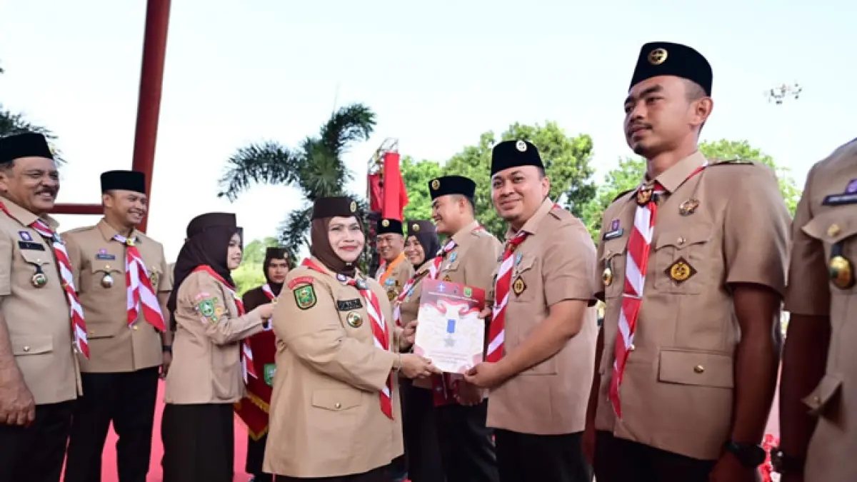 Bupati Hj Kasmarni menyerahkan penghargaan Lencana Pancawarsa kepada salah satu anggota Gerakan Pramuka dalam apel Hari Pramuka ke 65 di Lapangan Tugu, Bengkalis, Selasa (18/8/2026).(Istimewa)