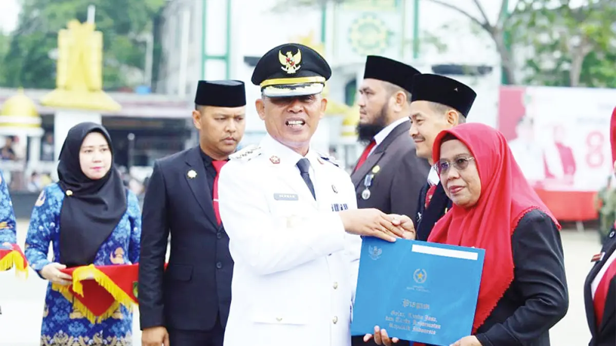 Bupati Indragiri Hilir Herman menyerahkan penghargaan Satyalancana Karya Satya secara simbolis kepada perwakilan ASN pada peringatan HUT ke-81 RI di Lapangan Gajah Mada Tembilahan, Senin (17/8/2026). (DISKOMINFO INHIL)