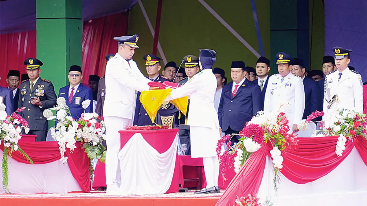 Bupati Inhu, Ade Agus Hartanto SSos MSi  menyerahkan bendera  merah putih kepada pembawa baki, Jia Nursiya Ramadhani dari SMAN 1 Rengat untuk dikibarkan, Senin (17/8/2026). (Diskominfotik Inhu untuk riau pos)
