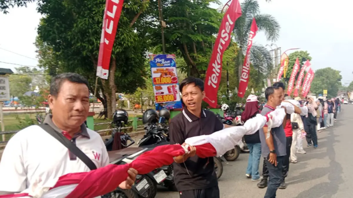 Kalangan pegawai di lingkungan Pemkab Kuansing membawa bendera merah putih untuk dipasang di sepanjang arena Pacu Jalur Tepian Narosa Teluk Kuantan, Selasa (18/8/2026). (Desriandi Candra/Riaupos.co) 