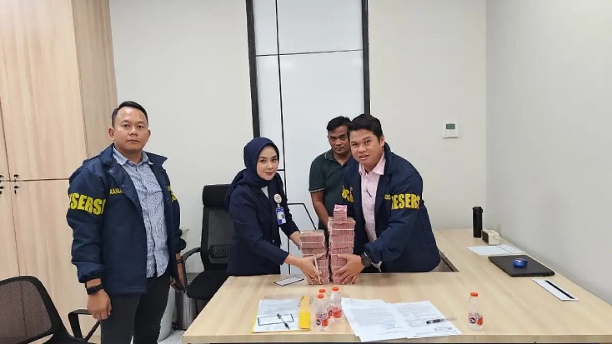 Kasubdit IV Ditreskrimsus Polda Riau AKBP Teddy Ardian (kiri) saat memperlihatkan tumpukan uang diduga hasil penjualan emas penambangan ilegal, Selasa (18/8/2026). (Polda Riau)