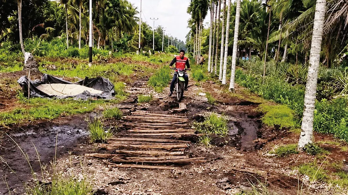 Warga melewati jalan semenisasi yang sudah ditambal menggunakan potongan kayu di Kecamatan Rangsang, Kepulauan Meranti, baru-baru ini. (WARGA RANGSANG UNTUK RIAU POS)