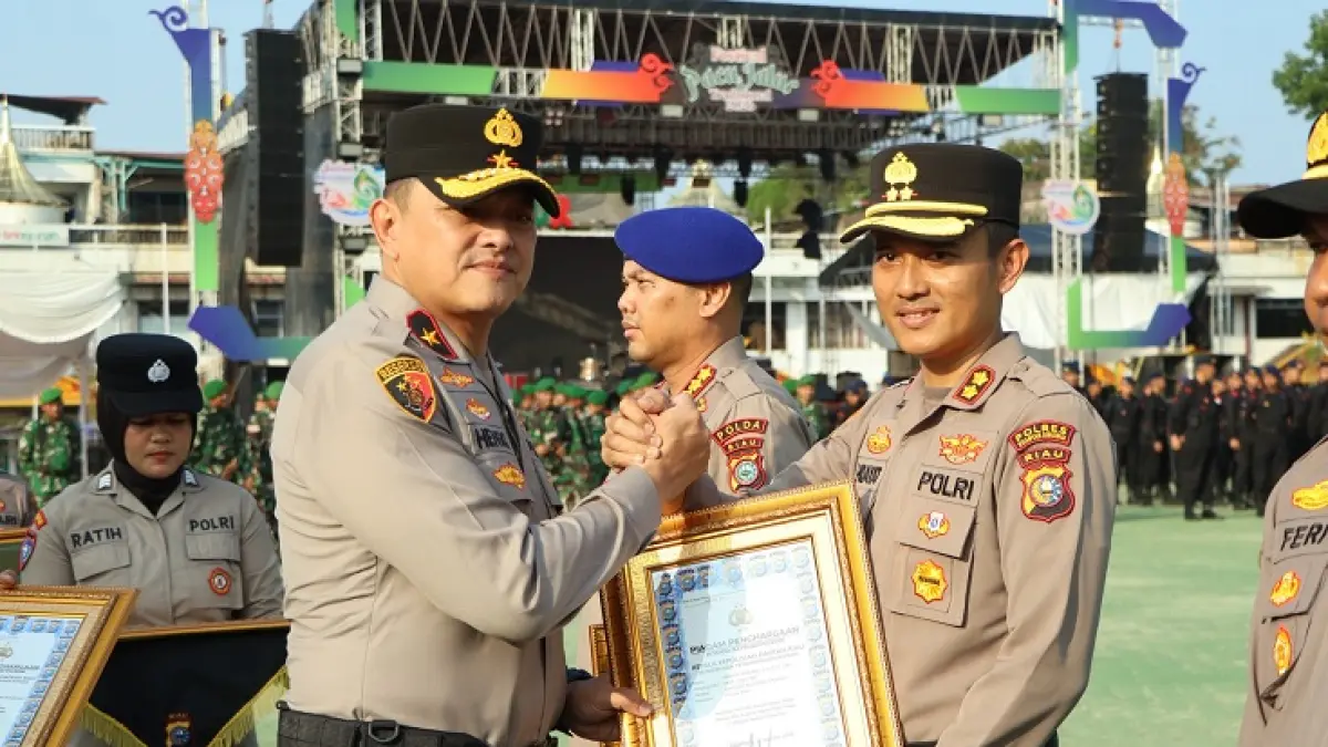 Wakapolda Riau Brigjen Pol Hengki Haryadi menyerahkan penghargaan pada Kapolres Kuansing AKBP Hidayat Perdana dalam pemberantasan PETI pada apel pasukan pengamanan pacu jalur, Selasa (18/8/2026) di Tepian Narosa Teluk Kuahtan. (Desriandi Candra/Riaupos.co)