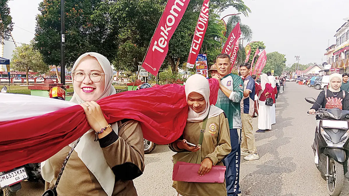 MEMBAWA BENDERA: Kalangan pegawai di lingkungan Pemkab Kuansing membawa bendera Merah Putih untuk dipasang di sepanjang arena pacu jalur Tepian Narosa Telukkuantan, Selasa (18/8/2026). (DESRIANDI CANDRA/RIAU POS)
