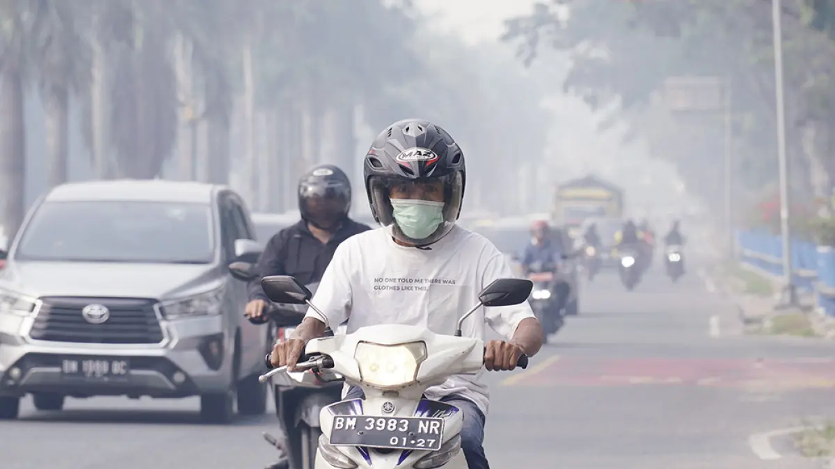 Pengendara sepeda motor memakai masker ketika melintas di Jalan Jenderal Sudirman, Pekanbaru  yang diselimuti kabut asap, Selasa (18/8/2026) pagi. (MHD AKHWAN/RIAU POS )