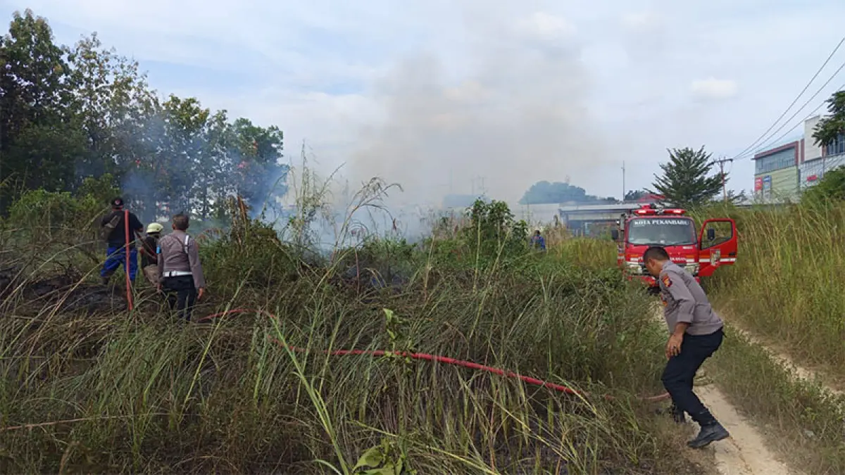Polisi mengawal proses pemadaman kebakaran lahan kosong di dekat Simpang SKA. (Prapti Dwi Lestari)
